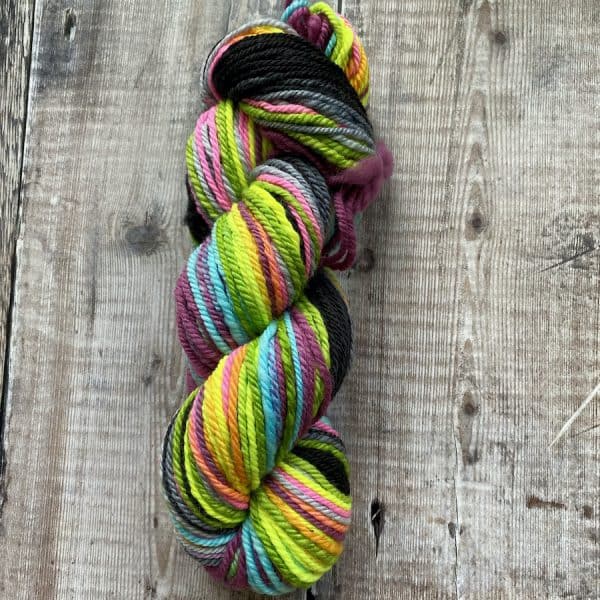 Bright neon, chain-plied hand spun yarn on a wooden background. Rainbow neon colours.