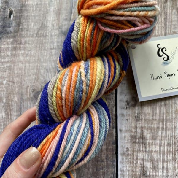 Hand holding a multicolour chain-plied hand spun yarn