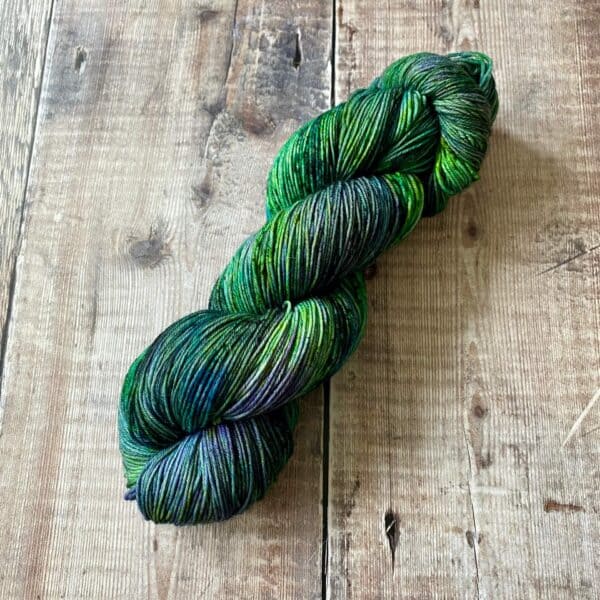 hand dyed yarn - green speckled skein on tabletop