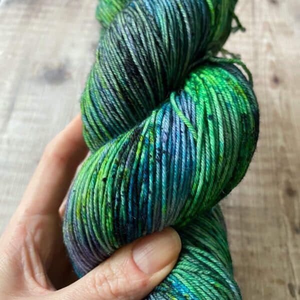 Green speckled hand dyed yarn held by Eleanor Shadow's hand