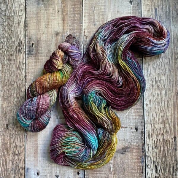 Jewel toned hand dyed yarn on table, flat lay view, one yarn is skeined, the other is lose