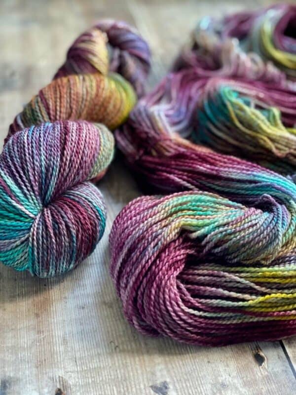 closeup of two jewel toned hand dyed yarns in the Autumn Harvest colourway