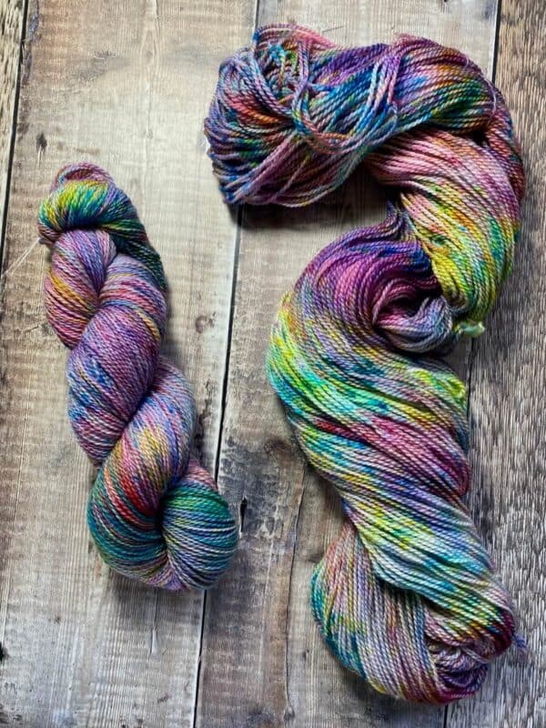 Two skeins of hand dyed jewel tone yarn with speckles, on table